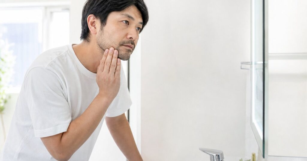 ヒゲ脱毛の効果を鏡で確認して悩む男性の写真